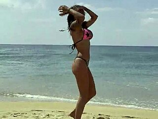 Monika Fox poses seductively in pink bikini on sunny beach.