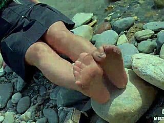 Goddess contrasts tan nylons with cute soles and toes teasing by the riverside outdoors