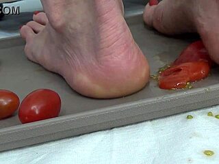 Housewife tramples ripe tomatoes under bare feet sensually