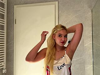Watch this sexy blonde coed tease her satin-clad body in bathroom